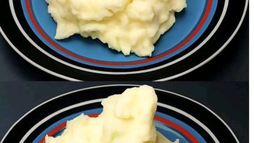 A bowl of creamy mashed potatoes, perfectly whipped to a smooth texture, topped with a pat of butter and garnished with freshly chopped parsley.