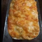 A creamy bowl of homemade macaroni and cheese with golden, melted cheese on top, garnished with a sprinkle of parsley.