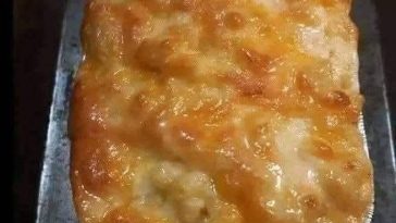 A creamy bowl of homemade macaroni and cheese with golden, melted cheese on top, garnished with a sprinkle of parsley.