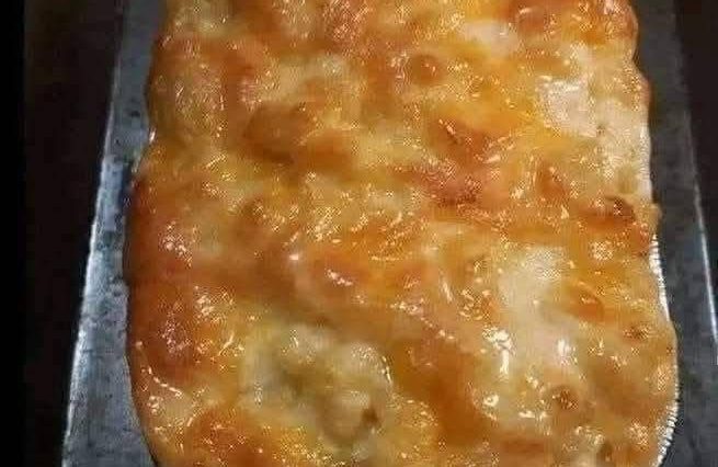 A creamy bowl of homemade macaroni and cheese with golden, melted cheese on top, garnished with a sprinkle of parsley.